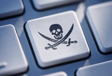 Teclado de computador, onde uma das teclas está em destaque mostrando uma caveira, indicando software pirata.